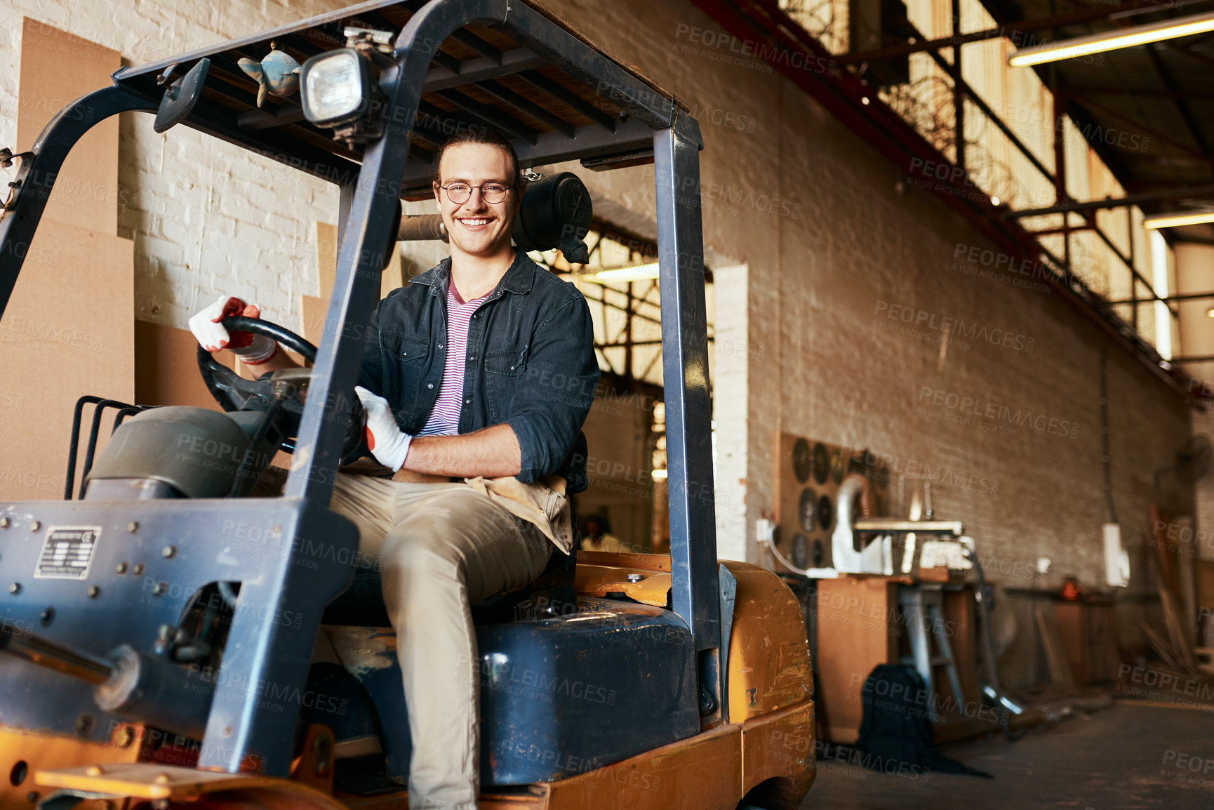 Buy stock photo Shot of a young male warehouse worker driving a forklift