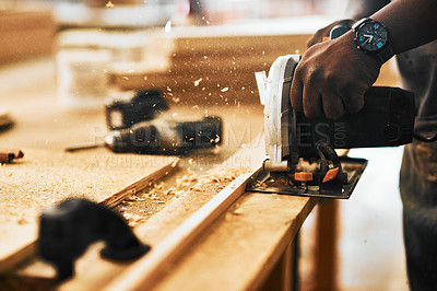 Buy stock photo Cropped shot of an unrecognizable carpenter using a circular saw to cut wood inside a workshop