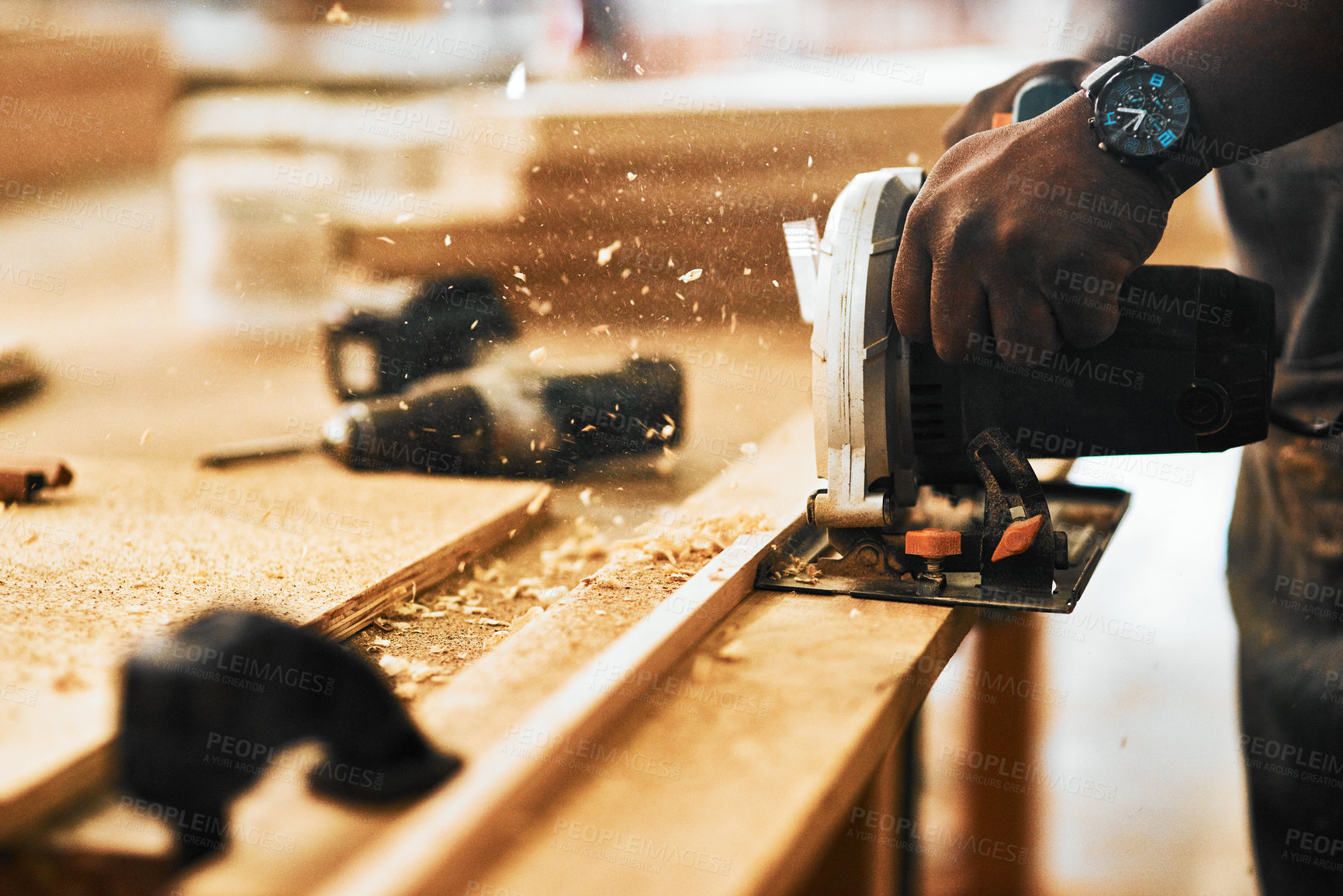 Buy stock photo Cropped shot of an unrecognizable carpenter using a circular saw to cut wood inside a workshop