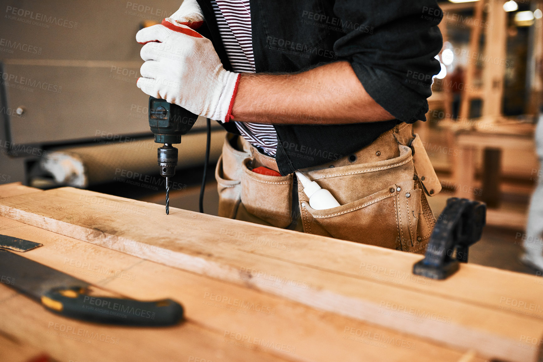 Buy stock photo Cropped shot of an unrecognizable carpenter using an electric drill inside a workshop