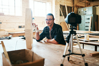 Buy stock photo Shot of young carpenter recording a tutorial of him making a wooden masterpiece on a video camera inside his workshop