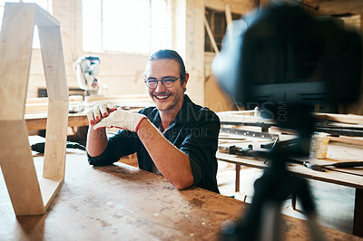 Buy stock photo Portrait of young carpenter recording a tutorial of him making a wooden masterpiece on a video camera inside his workshop