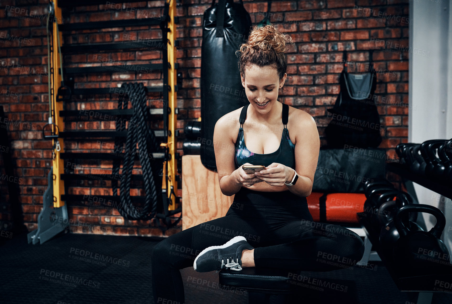 Buy stock photo Shot of a sporty young woman using a digital tablet while sitting in the gym