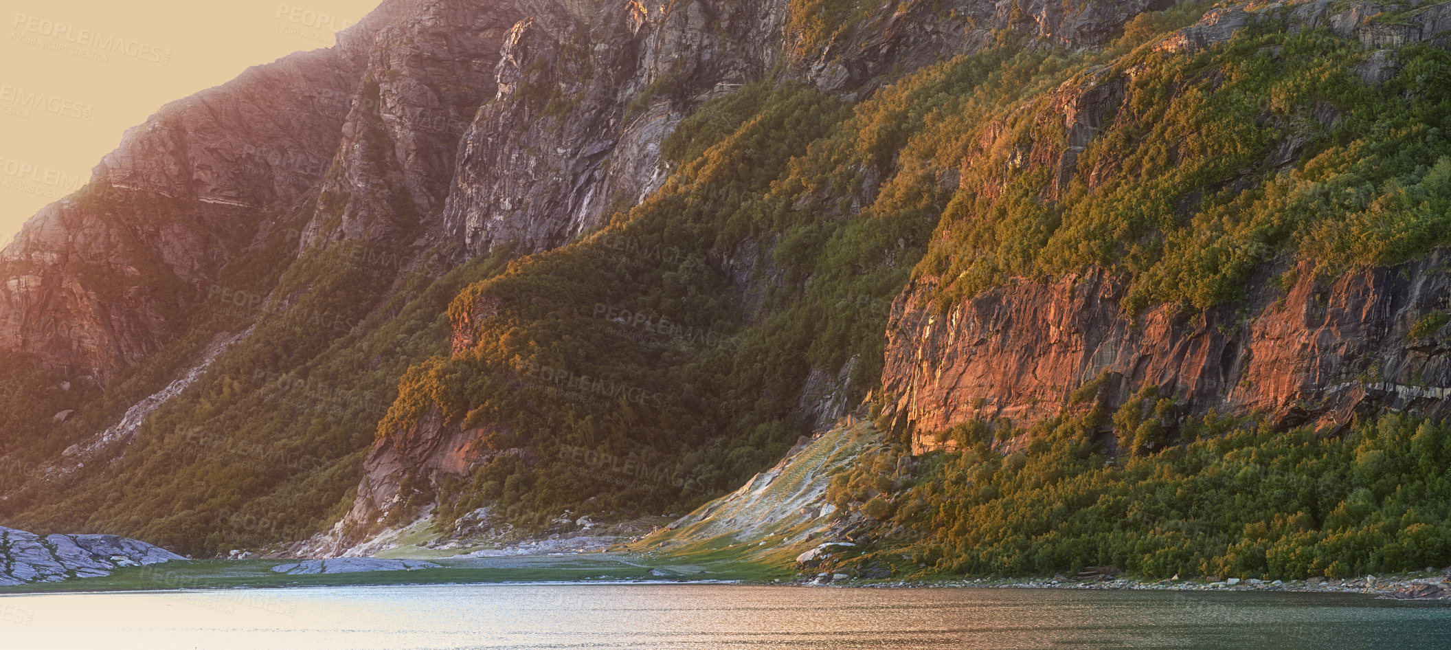 Buy stock photo Landscape view of lake water and mountains at sunset in Norway. Calm, serene, tranquil, ocean or sea at dawn in a remote, peaceful countryside. Relaxing nature fjord scenery with steep cliffs at dawn