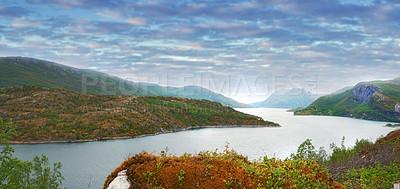 Buy stock photo Beautiful landscape of a lake or river with a blue sky background with copy space. Lush green hills with bright vibrant plants near still water with copyspace. Peaceful and scenic view a pond