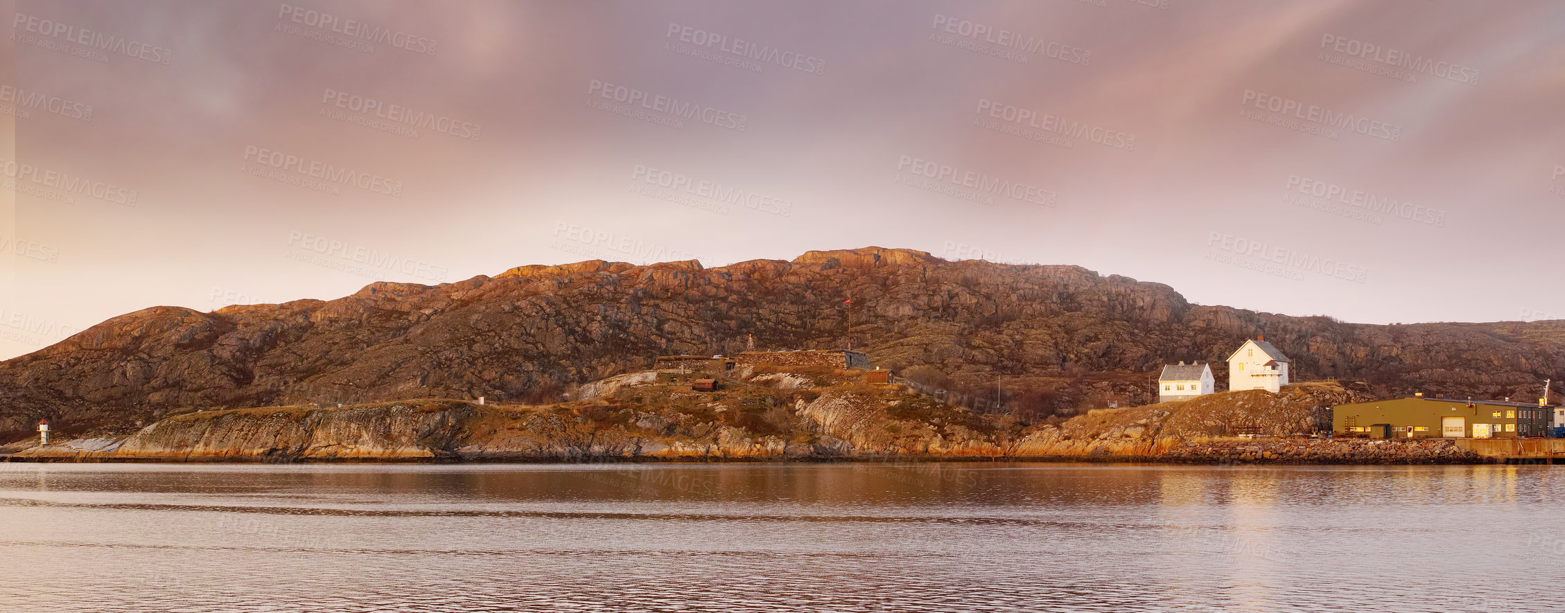 Buy stock photo Sea landscape near a mountain with houses on a hill. The ocean or a large lake with residential buildings in the distance outdoors during sunset on a cloudy day. Perfect location for summer vacation