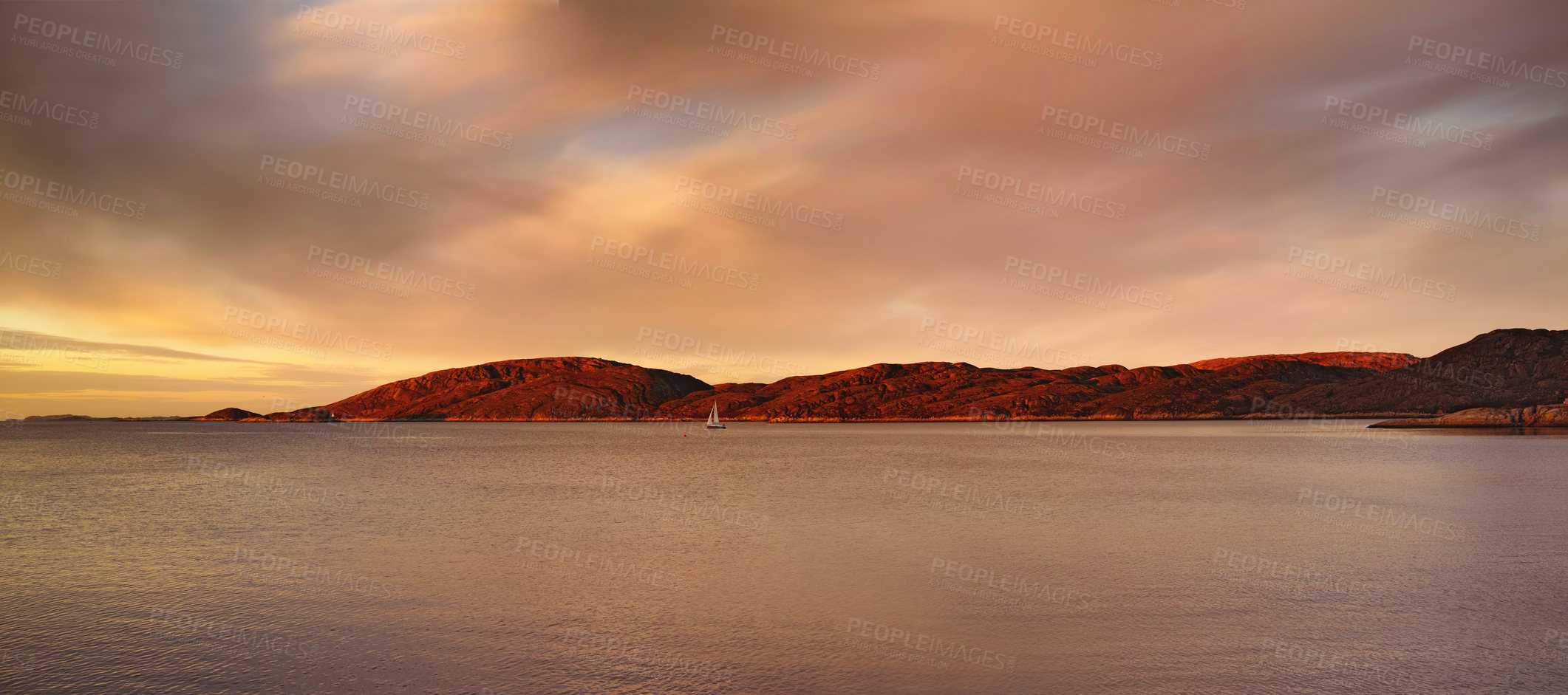 Buy stock photo Distant sea landscape near a mountain with a small sailboat in the water. The ocean, beach, or large lake with a boat in the distance near a hill outdoors during sunset on a cloudy day