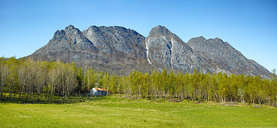 Buy stock photo Landscape view of mountains, blue sky and copy space in a remote countryside field in Norway. Discovering scenic pine tree woods or forests and a cabin in a serene, tranquil and quiet nature meadow