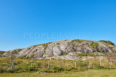 Buy stock photo Landscape view of a boulder on a field during summertime in Nordland, Norway. Copyspace of a rock on a lush green hill on the countryside. Scenic view of nature and natural environment on a sunny day