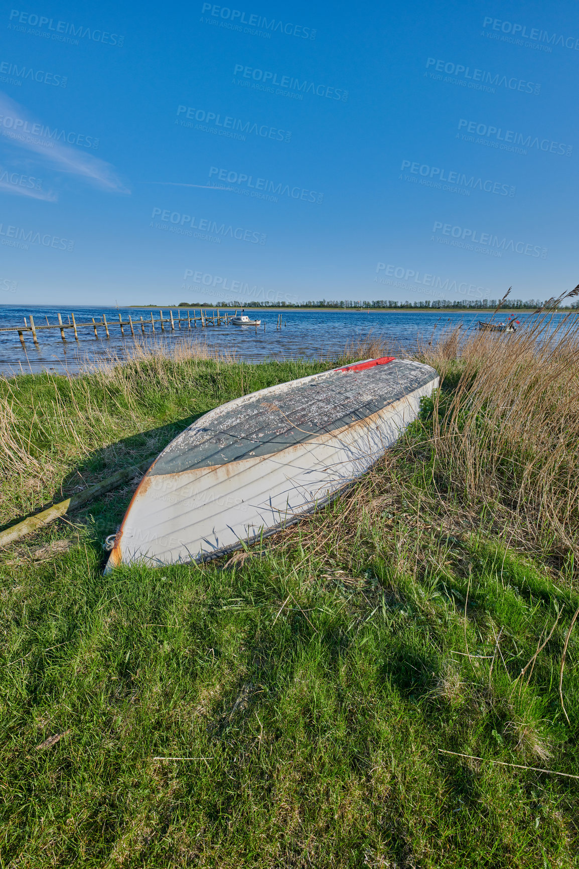 Buy stock photo An overturned abandoned wooden fishing boat on the shore of a lake.  A wooden fishing boat with a motor used in the sea or ocean to travel across a pond or a bay of water