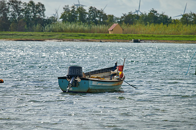 Buy stock photo An old fishing boat on a lake or bay of water. A wooden rowboat on the water, catching fish as a hobby or to sell during summer. Choppy current and an empty motorboat or weathered sea vessel