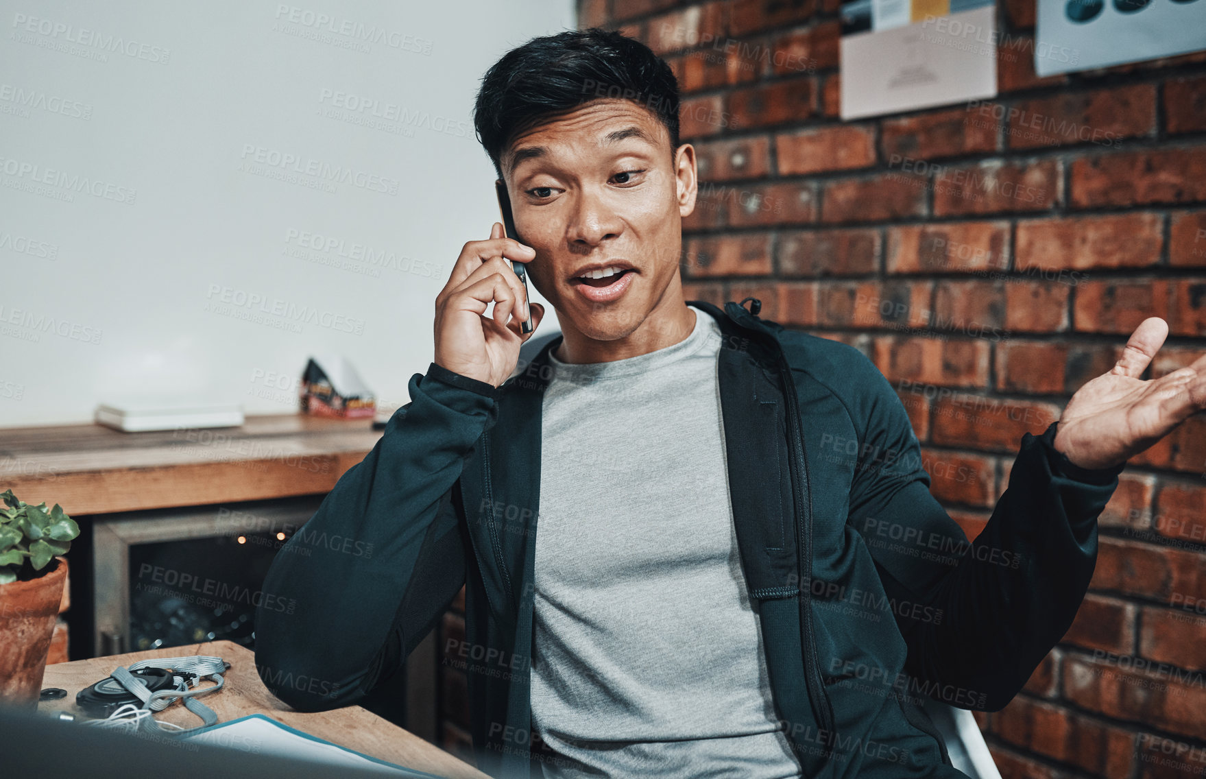 Buy stock photo Cropped shot of a handsome young male fitness instructor taking a phonecall while working in a gym