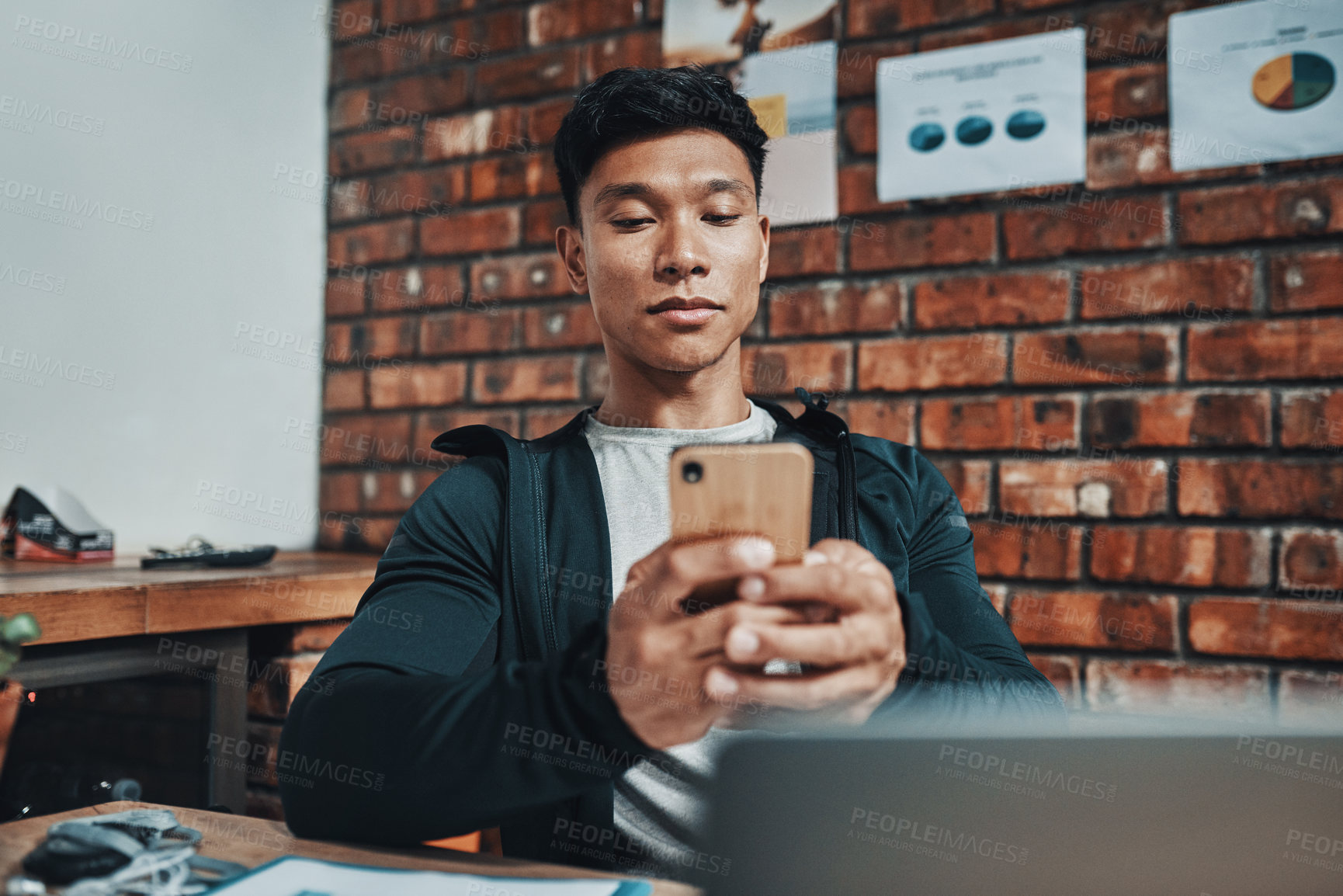 Buy stock photo Cropped shot of a handsome young male fitness instructor using a smartphone while working in a gym