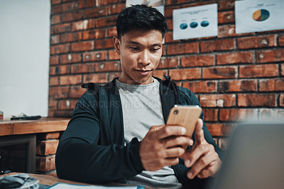 Buy stock photo Cropped shot of a handsome young male fitness instructor using a smartphone while working in a gym