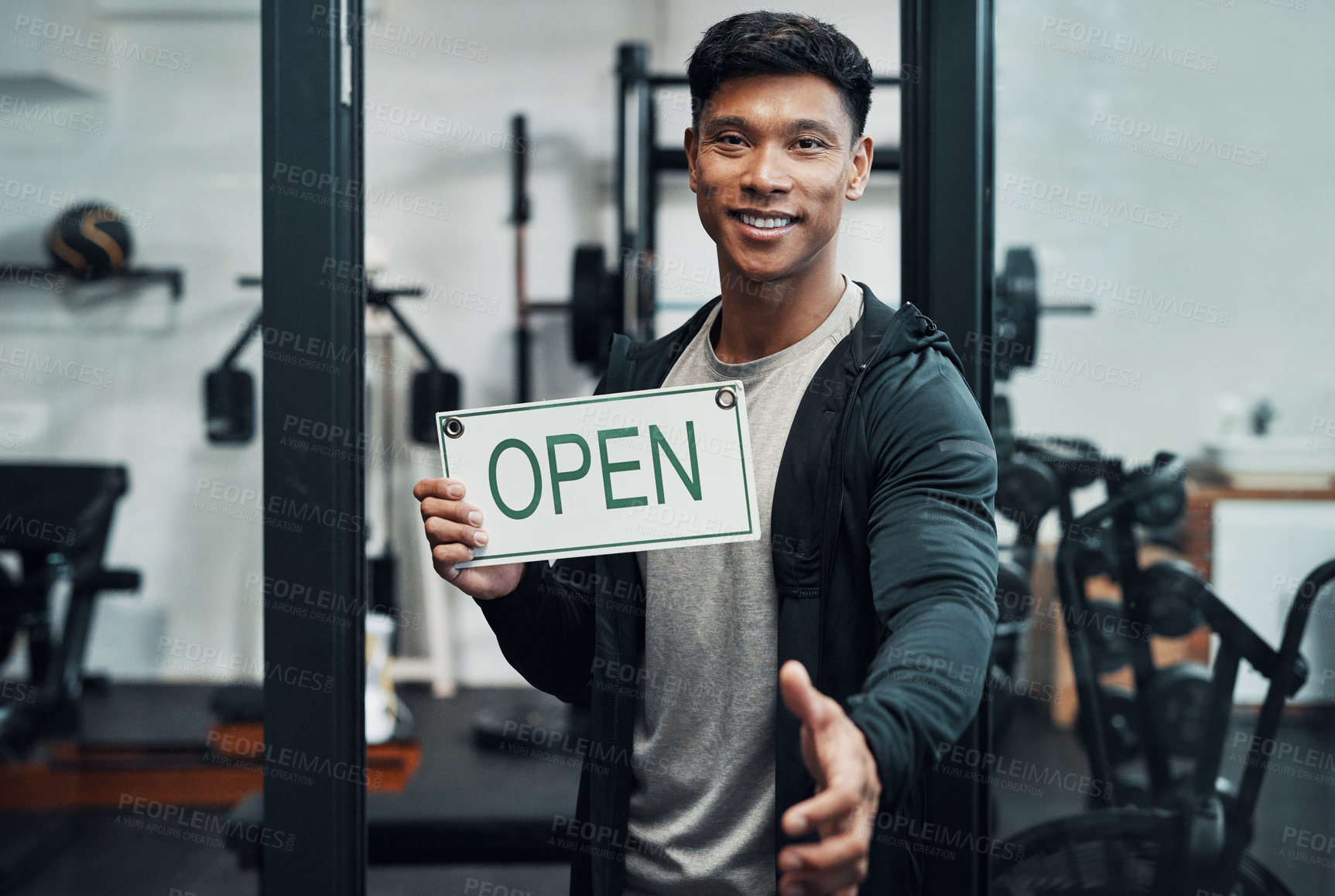 Buy stock photo Cropped portrait of a handsome young male fitness instructor extending his hand for a handshake while holding up a sign that says 