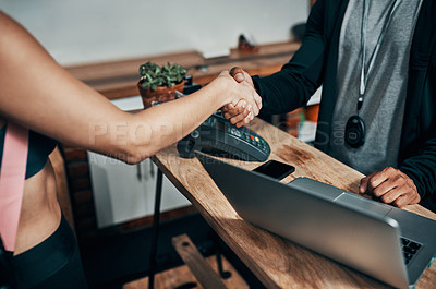 Buy stock photo Cropped shot of an unrecognizable male fitness instructor shaking hands with a gym member at the reception of a gym