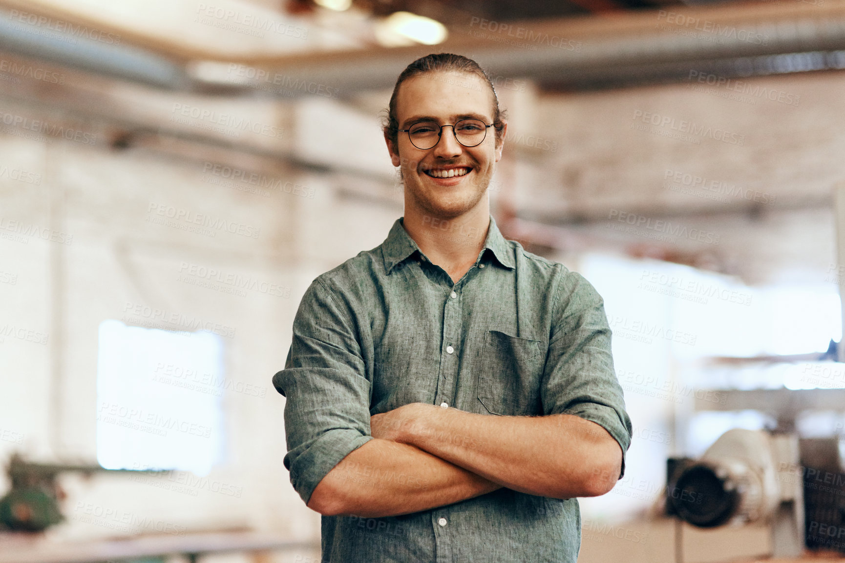 Buy stock photo Portrait of a young carpenter posing with his arms folded inside a workshop