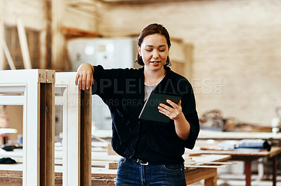 Buy stock photo Shot of a young female carpenter using a digital tablet while working inside her workshop