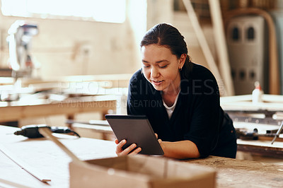 Buy stock photo Cropped shot of a young female carpenter using a digital tablet while working inside her workshop