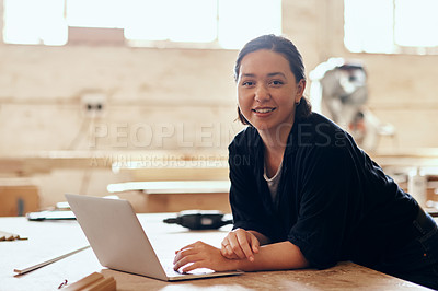 Buy stock photo Portrait of a young female carpenter using a laptop while working inside her workshop