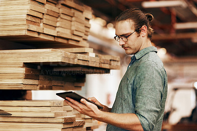 Buy stock photo Cropped shot of a young carpenter using a digital tablet while working inside his workshop