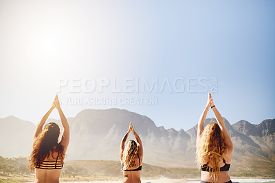 Buy stock photo Rearview shot of three young women practising yoga on the beach