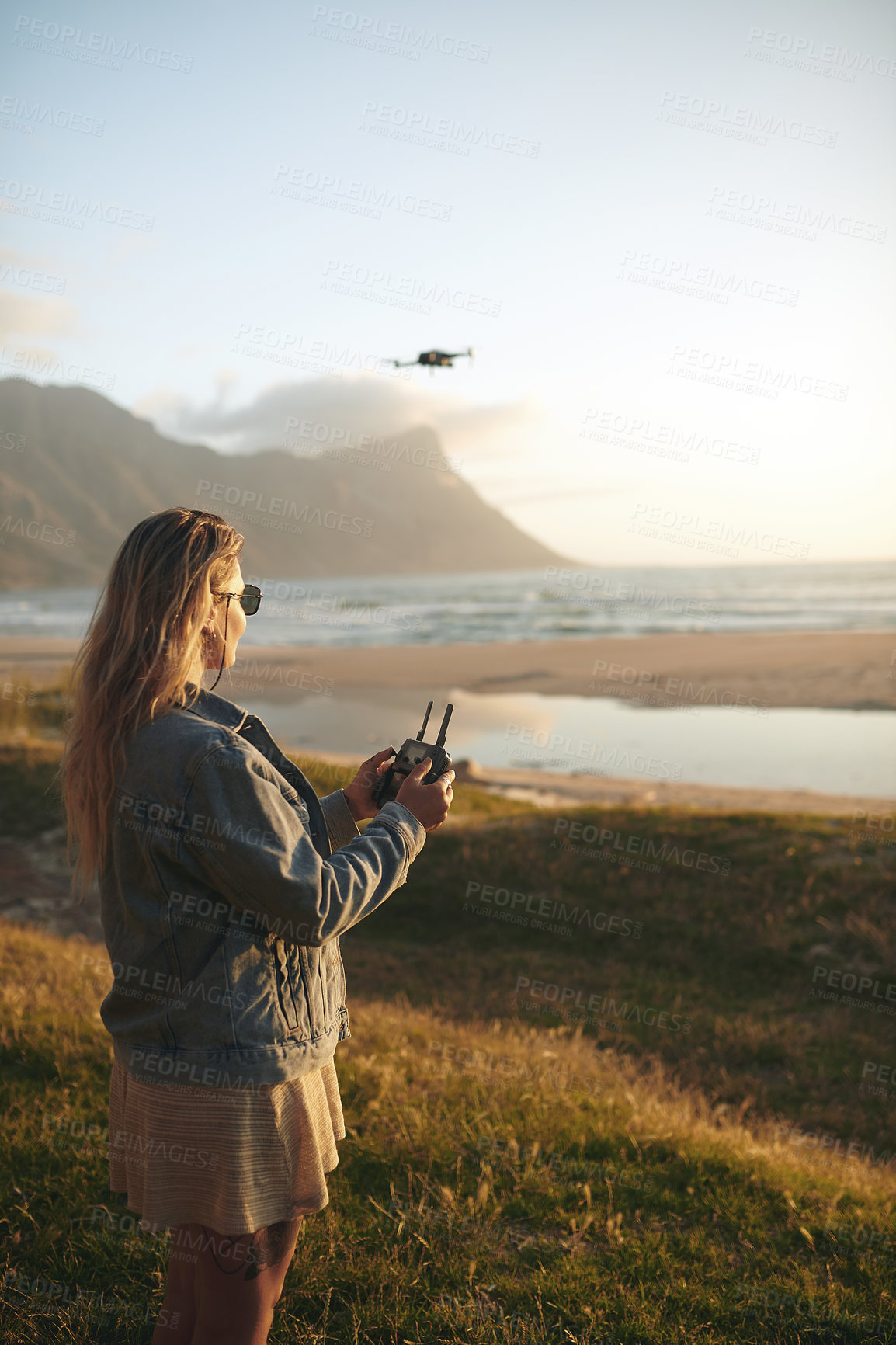 Buy stock photo Cropped shot of an attractive young woman flying a drone outdoors