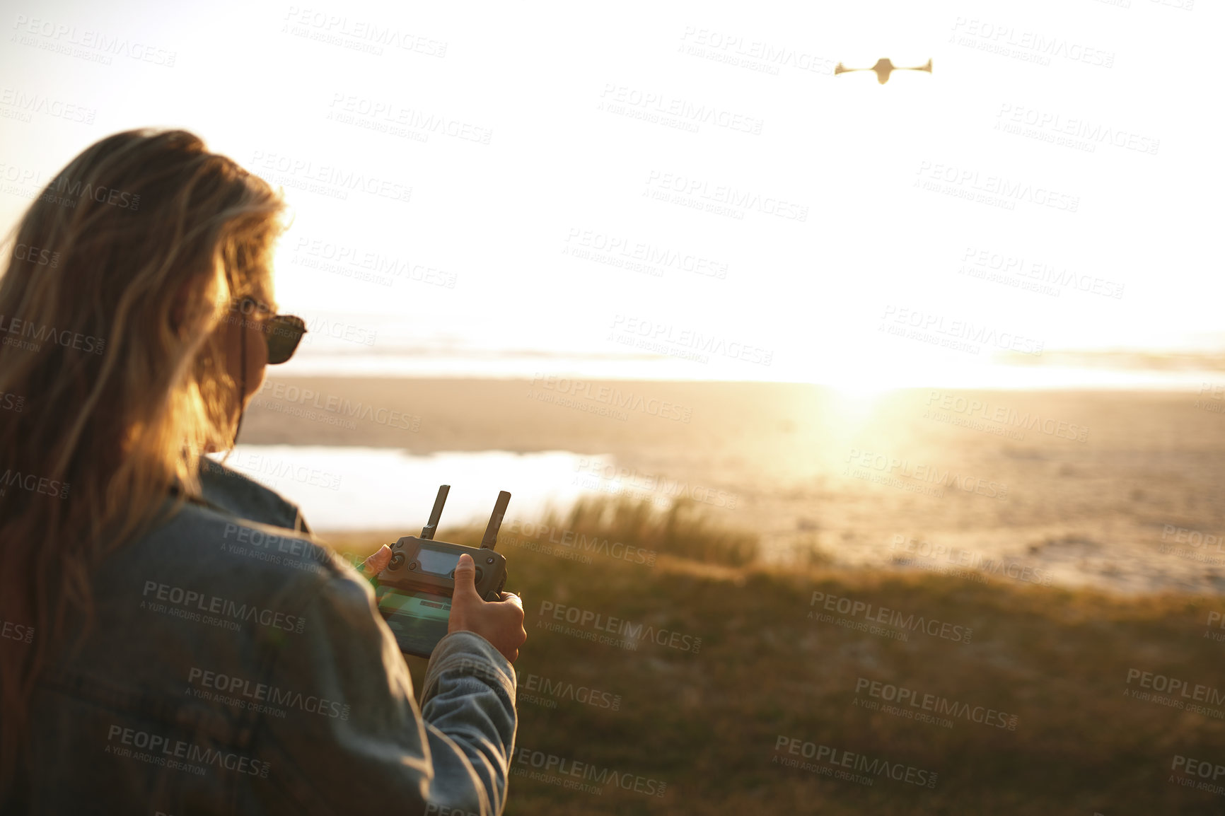 Buy stock photo Cropped shot of an attractive young woman flying a drone outdoors