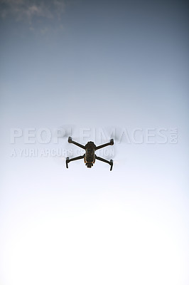 Buy stock photo Low angle shot of a drone flying high in the sky