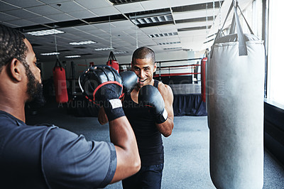 Buy stock photo Shot of a male boxer practising his moves with his coach