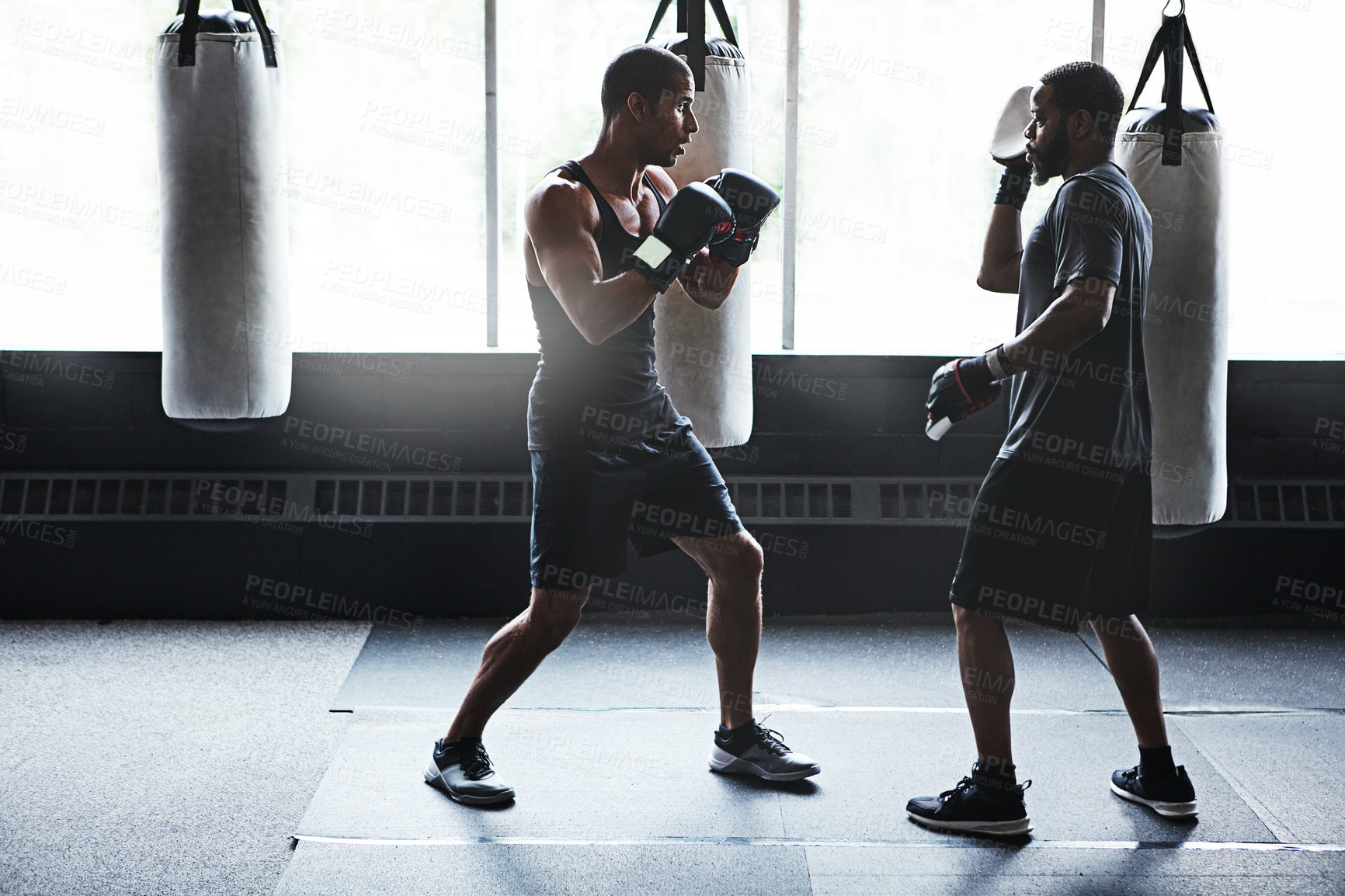 Buy stock photo Shot of a male boxer practising his moves with his coach