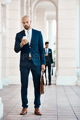 Buy stock photo Shot of a young handsome businessman using a cellphone outside