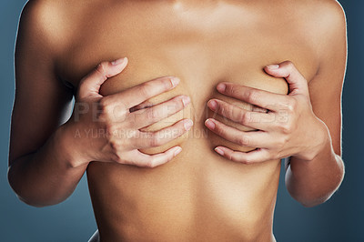 Buy stock photo Studio shot of an unrecognizable woman examining her breasts against a grey background