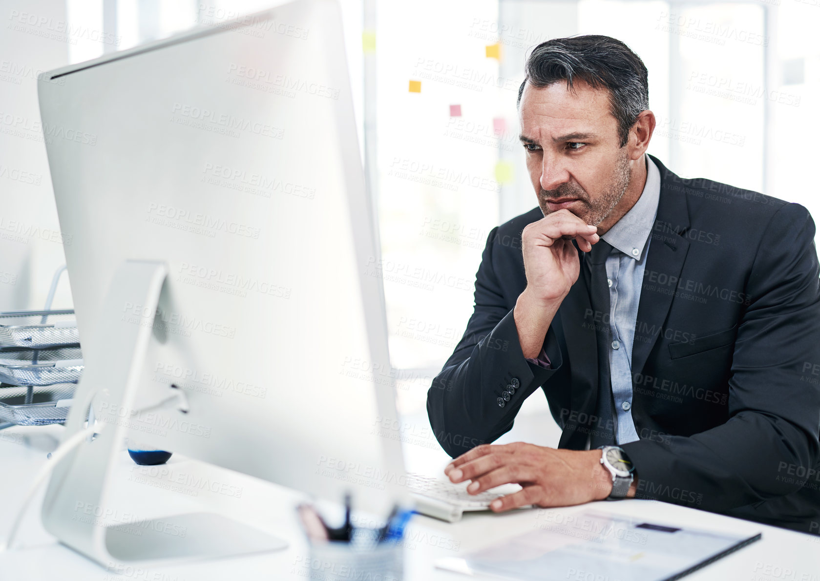 Buy stock photo Shot of a mature businessman working on a computer in an office