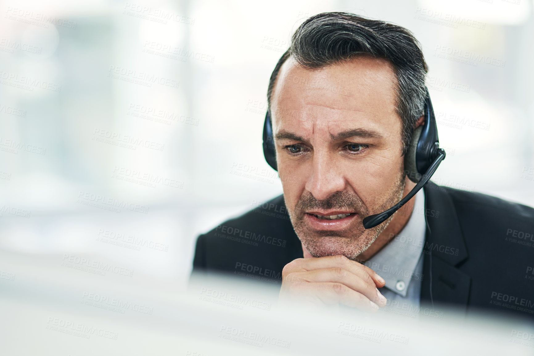 Buy stock photo Shot of a mature businessman using a headset while working on a computer in an office