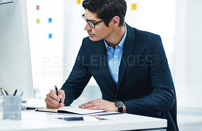Buy stock photo Shot of a young businessman writing notes in an office
