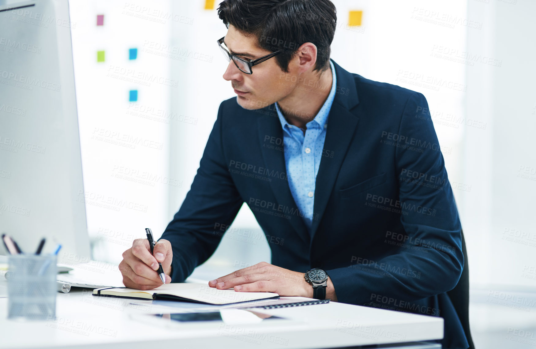 Buy stock photo Shot of a young businessman writing notes in an office