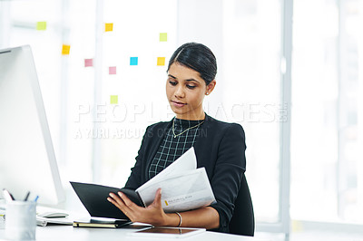 Buy stock photo Shot of a young businesswoman going through a folder in an office