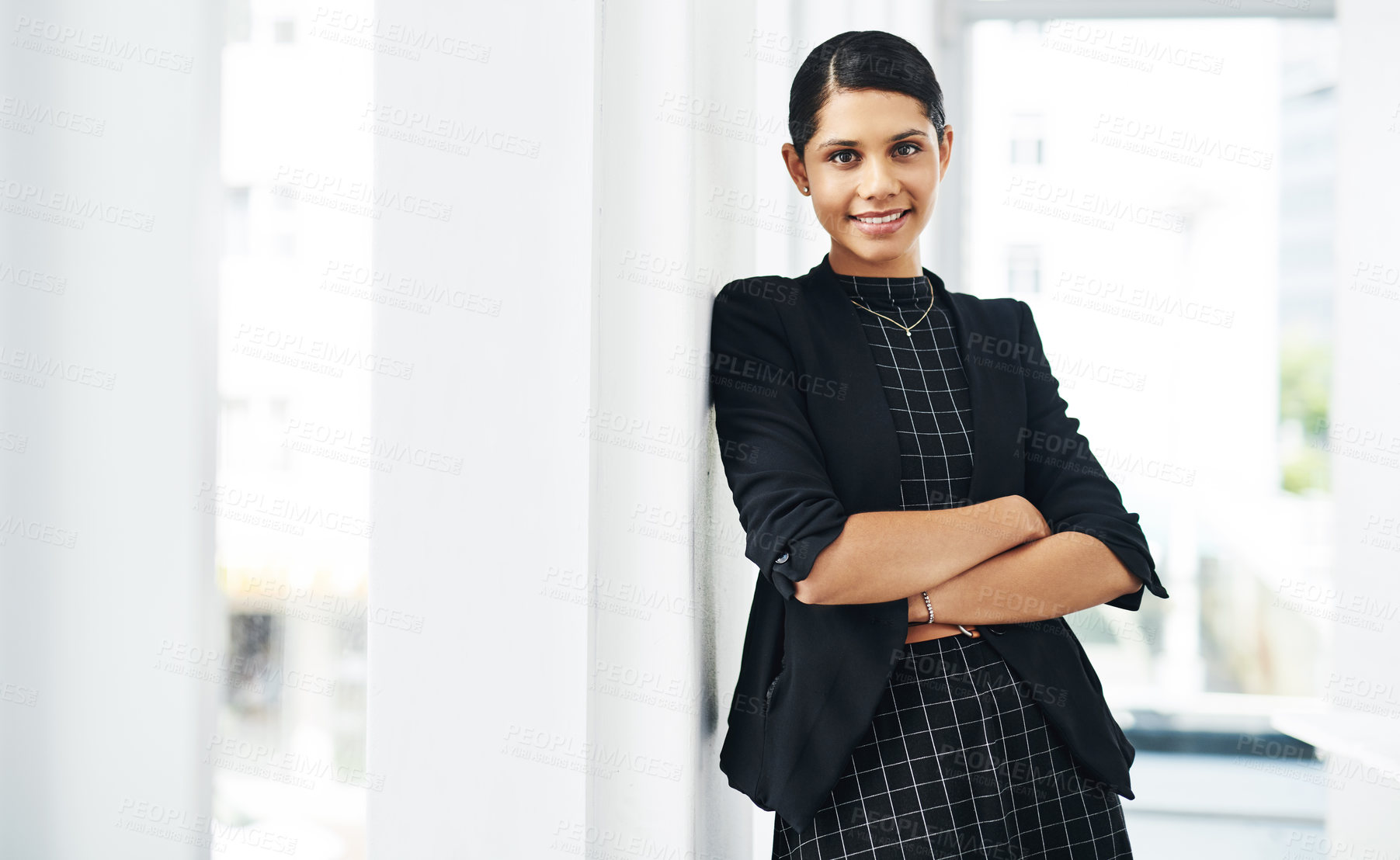 Buy stock photo Cropped portrait of an attractive young businesswoman standing with her arms folded in a modern office