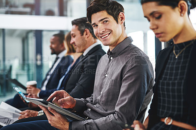Buy stock photo Cropped shot of a handsome young businessman using a digital tablet while sitting in line for an interview in a modern office