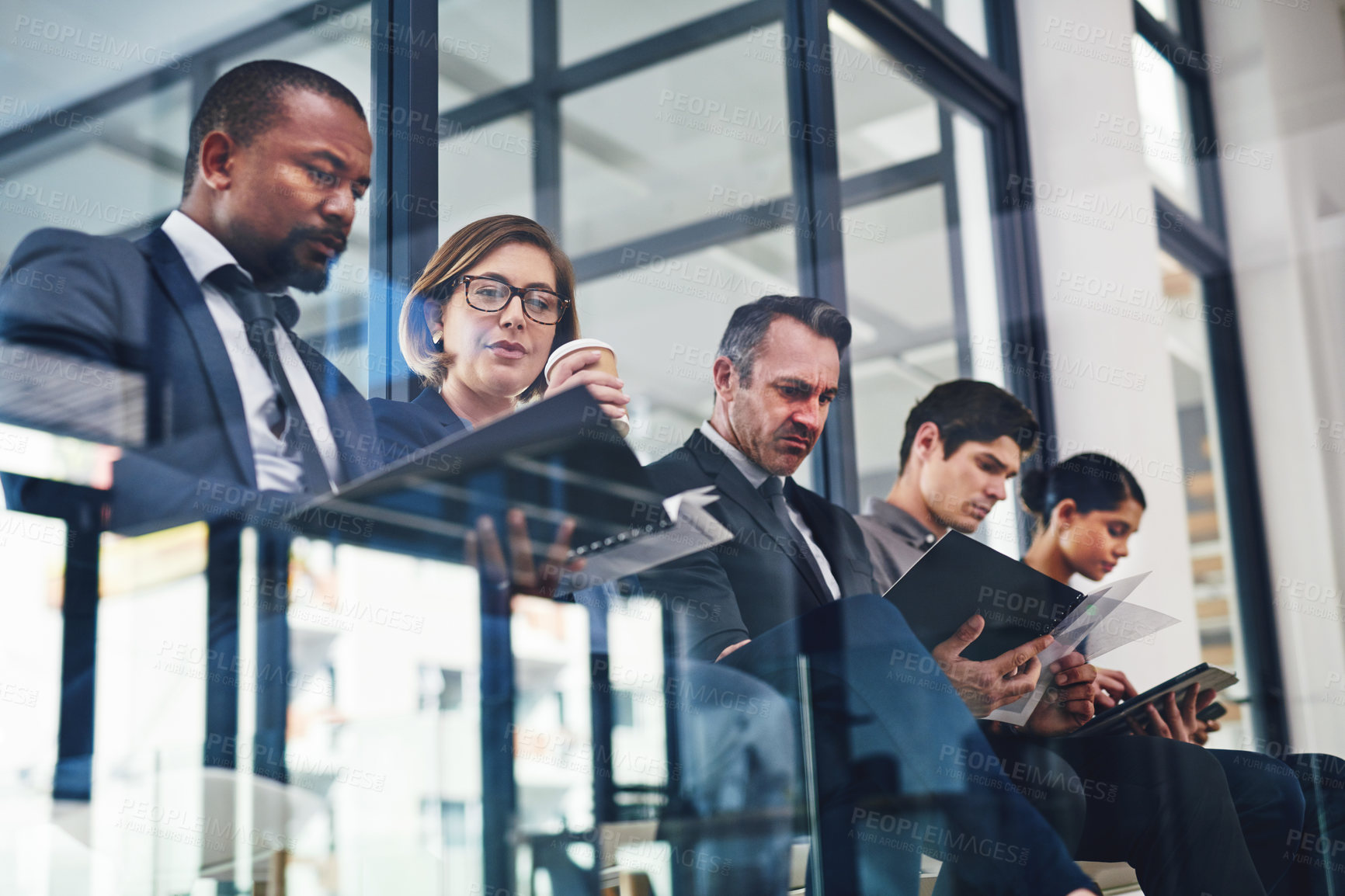 Buy stock photo Cropped shot of a diverse group of businesspeople sitting in line for an interview in a modern office