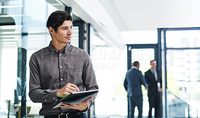 Buy stock photo Cropped shot of a handsome young businessman looking thoughtful while holding a digital tablet in a modern office