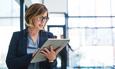 Buy stock photo Cropped shot of an attractive young businesswoman using a digital tablet in an office with her colleagues in the background