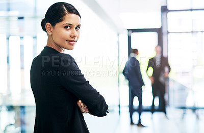 Buy stock photo Cropped portrait of an attractive young businesswoman standing with her arms folded in an office with her colleagues in the background