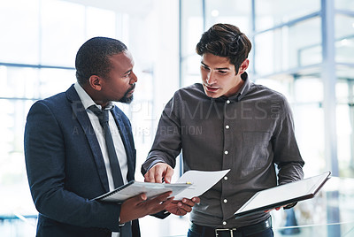 Buy stock photo Cropped shot of two young businessmen having a discussion while standing in a modern office