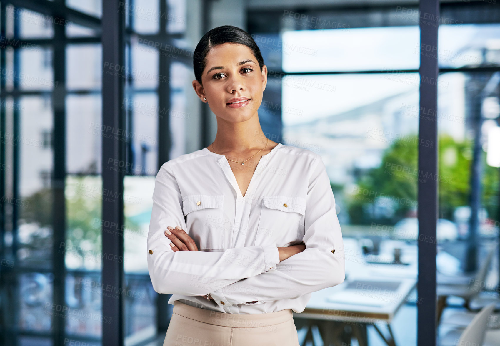 Buy stock photo Cropped portrait of an attractive young businesswoman standing with her arms folded in a modern office