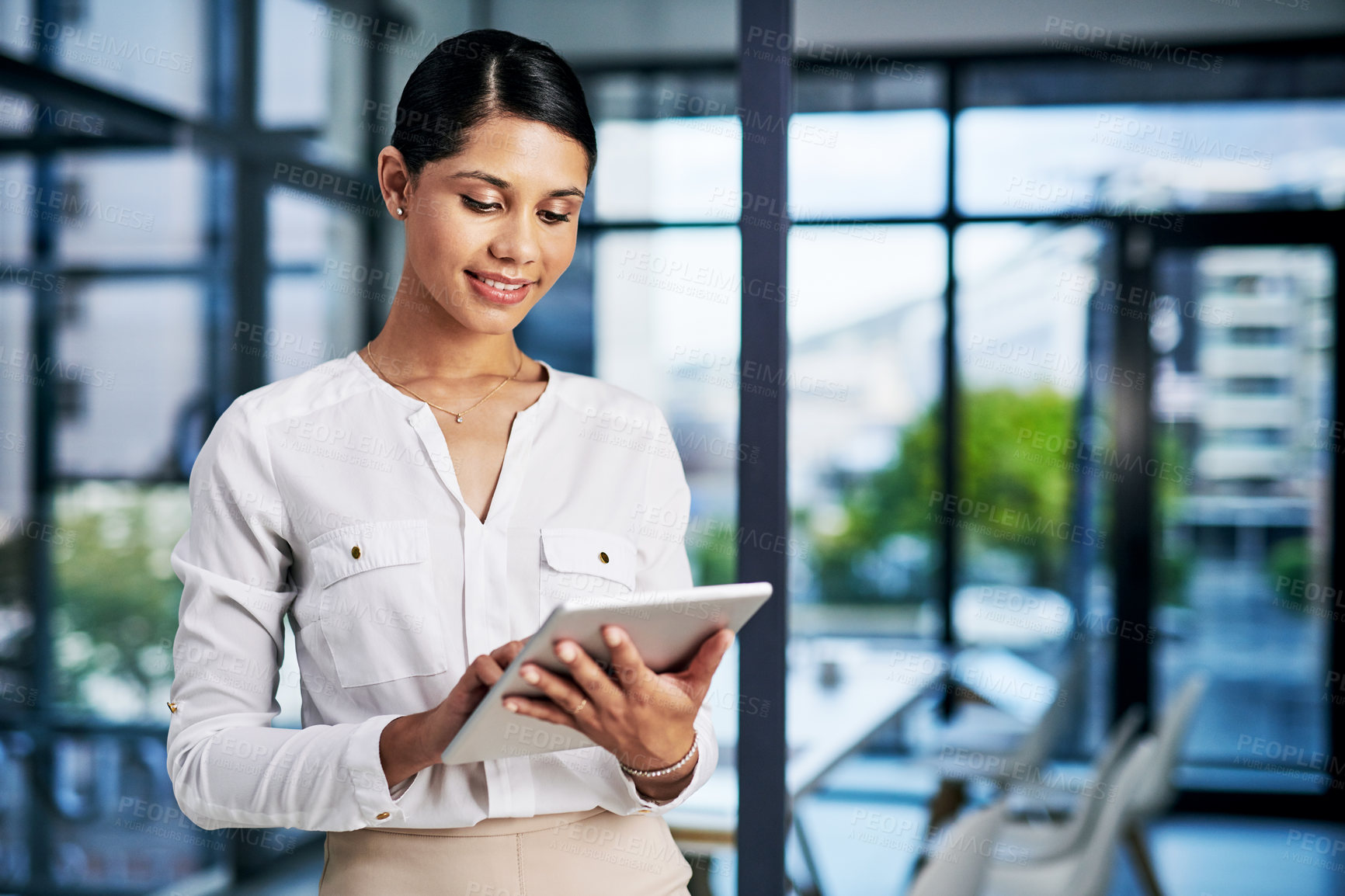 Buy stock photo Cropped shot of an attractive young businesswoman using a digital tablet while standing in a modern office