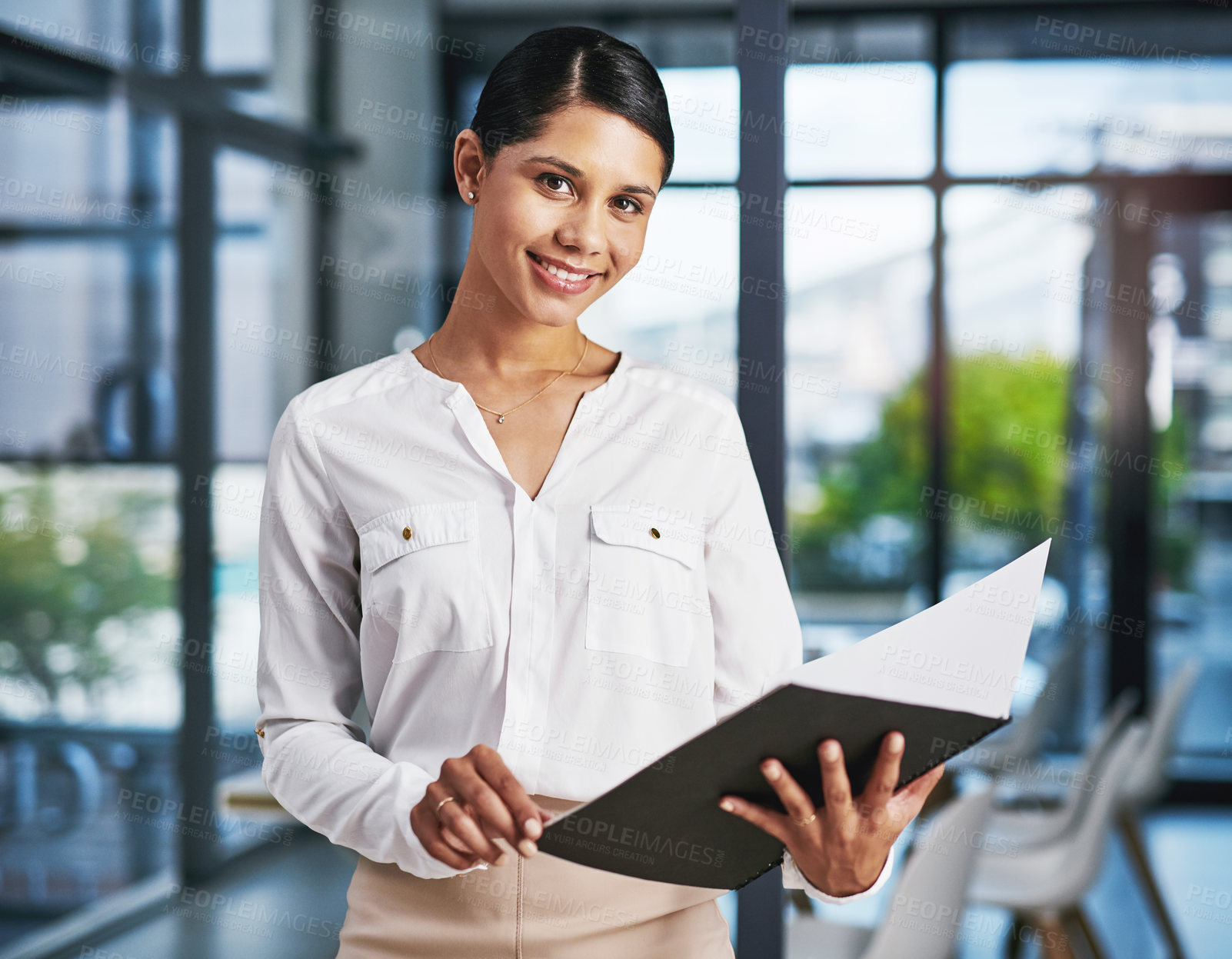 Buy stock photo Cropped portrait of an attractive young businesswoman smiling while holding a file in a modern office