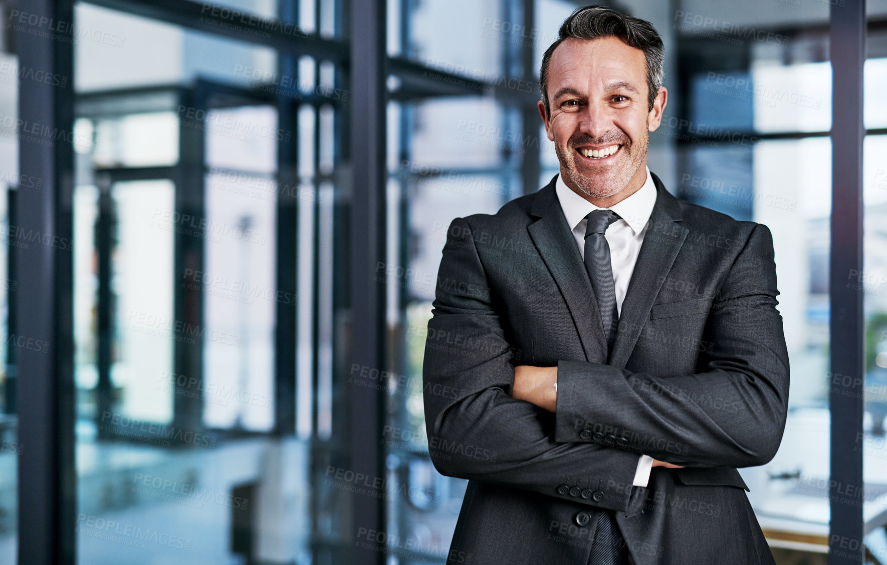 Buy stock photo Cropped portrait of a handsome mature businessman smiling while standing with his arms crossed in a modern office