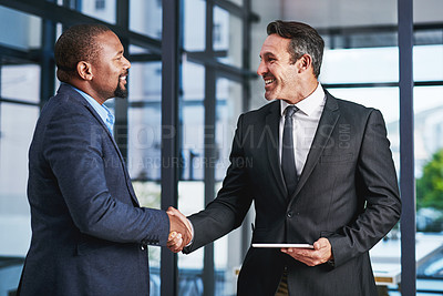 Buy stock photo Cropped shot of two handsome middle aged businessmen shaking hands in a modern office